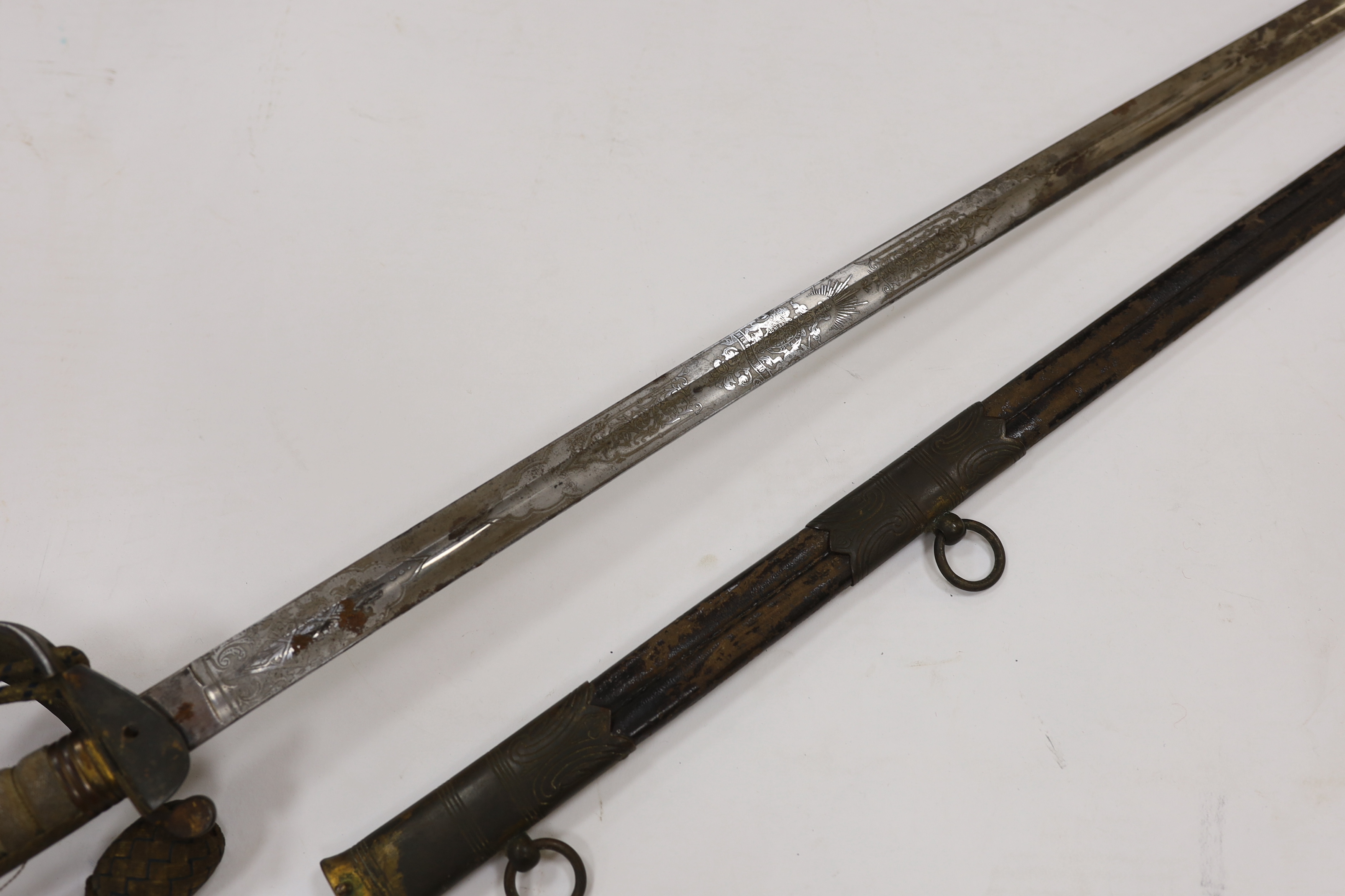 A late Victorian naval officer’s sword of the Royal Naval Reserve, regulation hilt with folding guard and bullion dress knot, in its leather scabbard with brass mounts